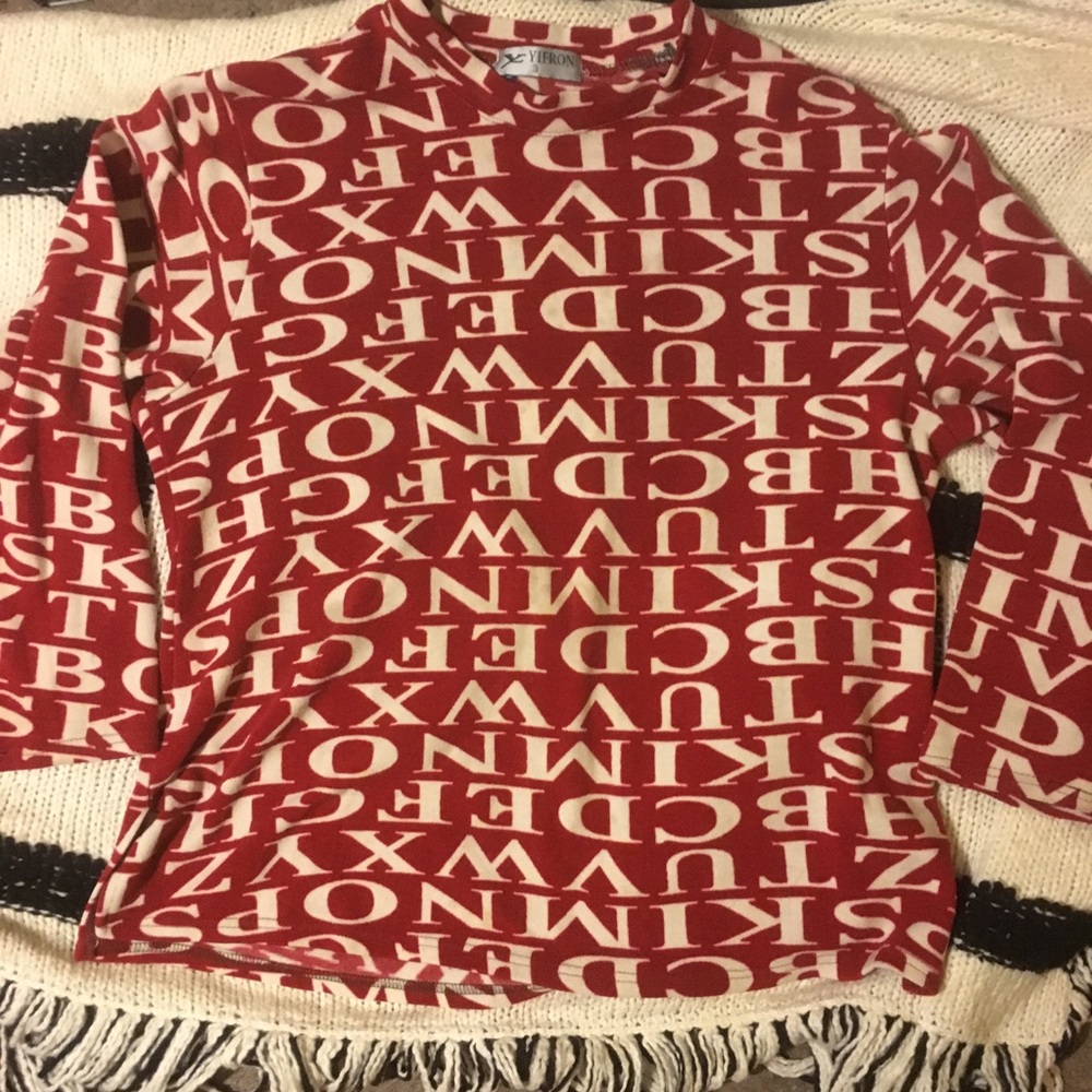 Cranberry colored sweater covered in white letters